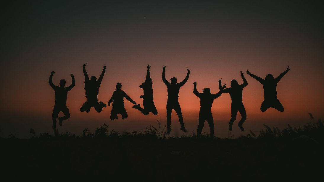 Silhouette of People Jumping on Field during Sunset